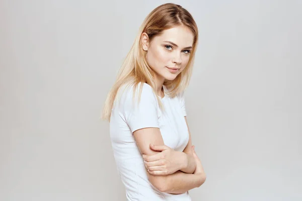 Симпатичная блондинка в белой футболке жест с руками стиль жизни светлый фон — стоковое фото