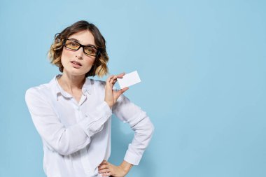 Mavi arka planda elinde kartvizit gözlüğü olan bir kadın. Kopya alanı kesilmiş görünüm