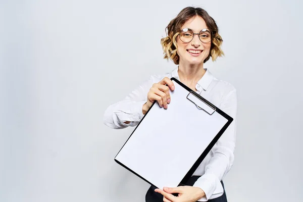 Деловая женщина с папкой с белыми документами в руке на светлом фоне и моделью очков в стиле прически — стоковое фото