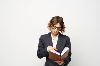Klasik takım elbiseli bir iş kadını elinde bir not defteri ve yüzünde gözlüklerle.
