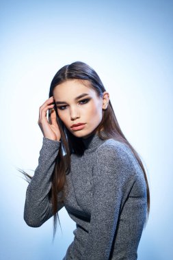 Çekici, parlak makyajlı bir kadın zarif bir modelle saçlarını düzleştiriyor.