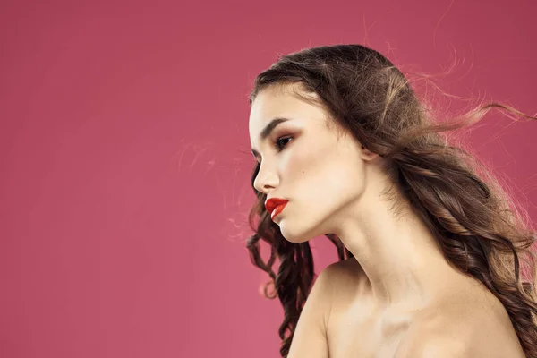 Schöne brünette Frau mit Make-up im Gesicht auf rosa Hintergrund nackte Schultern — Stockfoto