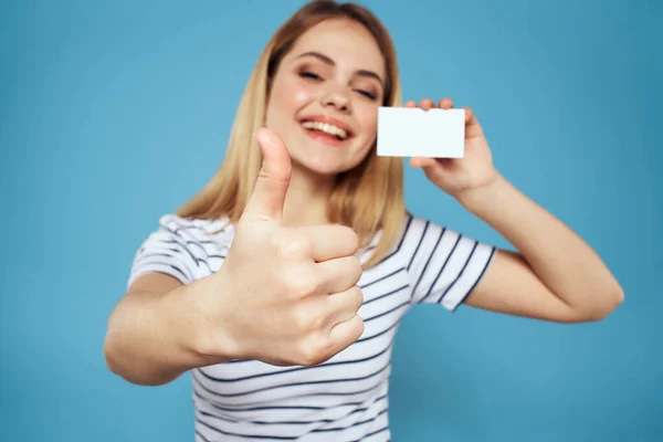 Femme avec une carte de visite dans ses mains un T-shirt rayé fond bleu Espace de copie — Photo