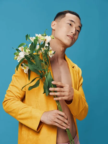 Homem sonhador com um buquê de flores e um casaco amarelo, tronco nu — Fotografia de Stock