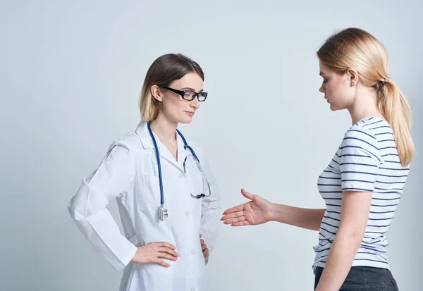 Женщина-врач и пациент пожимают руку на светлом фоне, общаясь медицина — стоковое фото