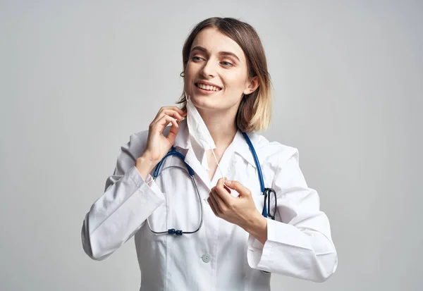 Mujer médico en máscara médica cogido de la mano cerca de la cara estetoscopio azul recortado ver —  Fotos de Stock