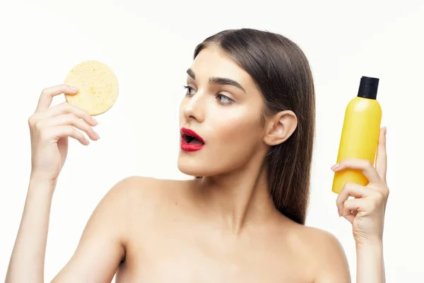 Vacker kvinna med en burk lotion och en mjuk svamp — Stockfoto