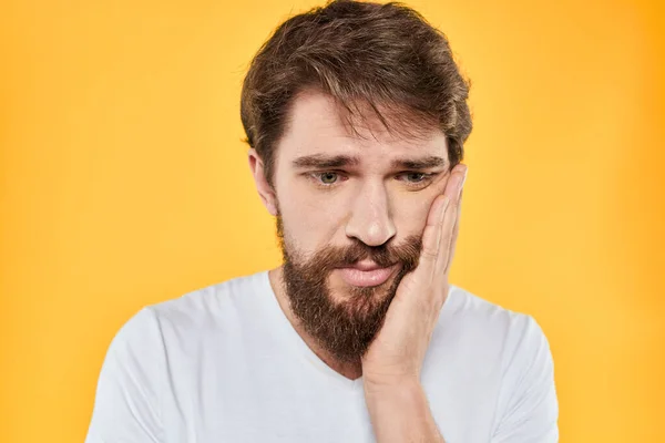 Man dengan ekspresi emosional putih t-shirt close-up studio latar belakang kuning — Stok Foto