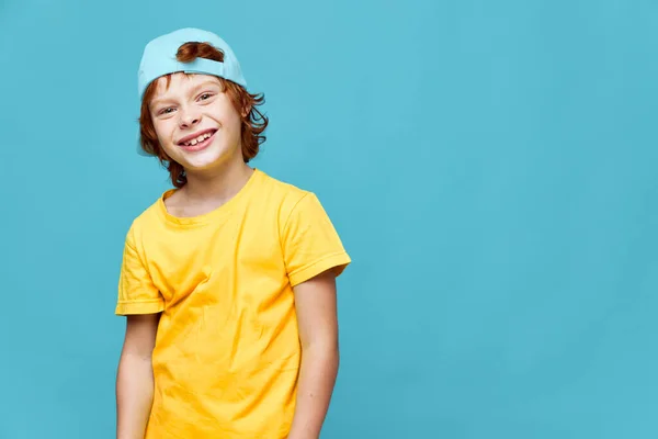 Porträtt av en rödhårig pojke ler gul t-shirt mössa på huvudet glädje — Stockfoto