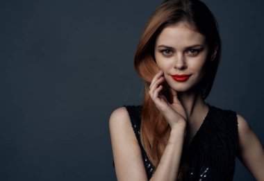 Kırmızı saçlı, gece makyajlı, siyah elbiseli hoş bayan. Arka planı gri.