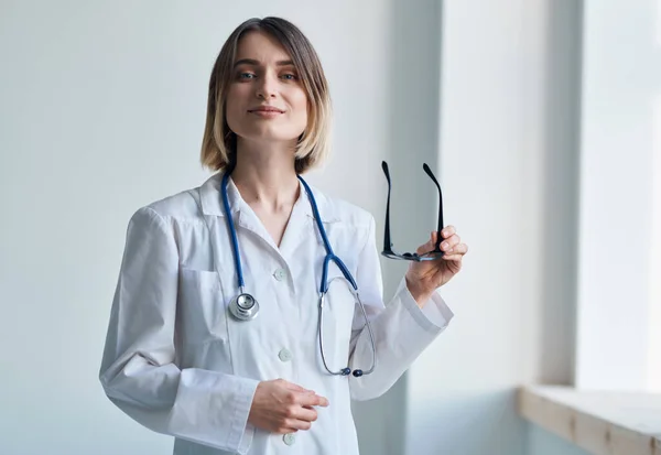 professional doctor woman holding glasses in her hand and stethoscope around her neck