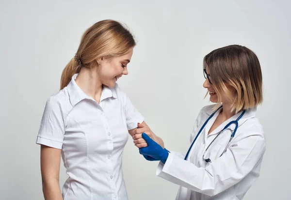 La doctora con una bata médica y guantes azules examina a una paciente en una vista recortada —  Fotos de Stock