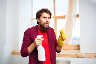 Kırmızı tişörtlü deterjan giyen adam ev işlerini temizliyor.