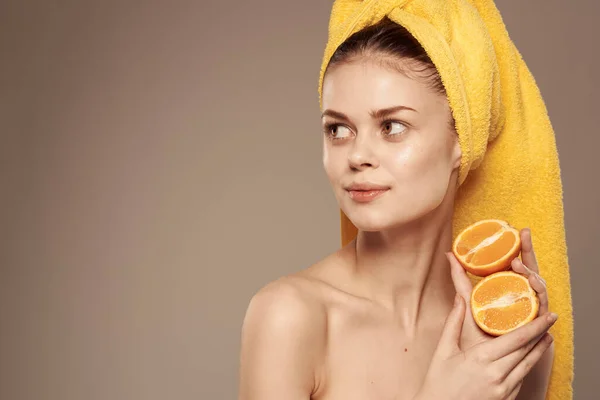 Mulher atraente com ombros nus com laranjas em mãos corte vista bege fundo — Fotografia de Stock