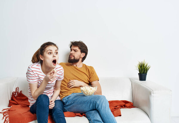 man and woman on sofa orange plaid bright room flower in a pot