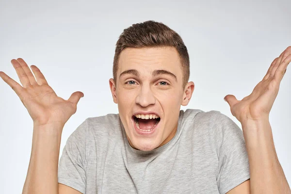 Cheerful emotional man gray t-shirt gesturing with hands studio lifestyle — Stock Photo, Image