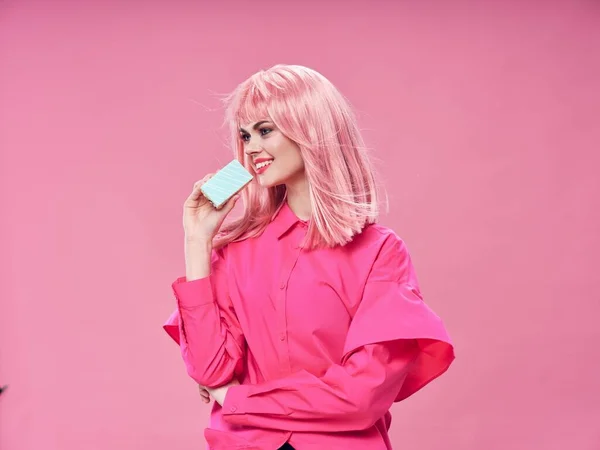 Happy woman with a cake in a pink shirt looks to the side of the birthday