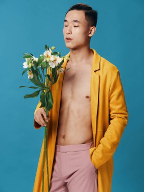 Romantik bir Asyalı adam elini cebinde tutar ve pembe pantolonunda bir buket çiçek.