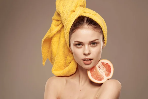 Woman with bare shoulders yellow towel on her head grapefruit in hands clean skin care — Stock Photo, Image