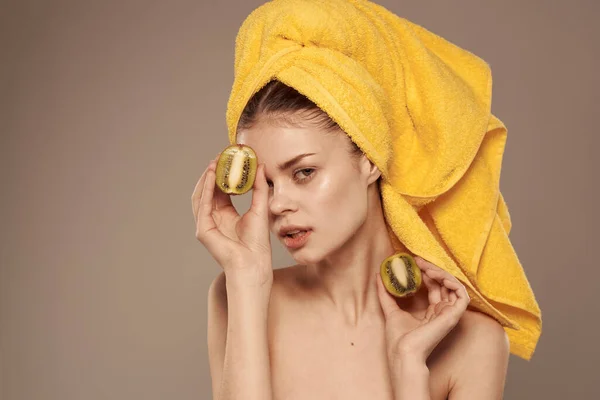 Woman with bare shoulders with a towel on her head kiwi in her hands clean skin fruit cosmetics — Stock Photo, Image