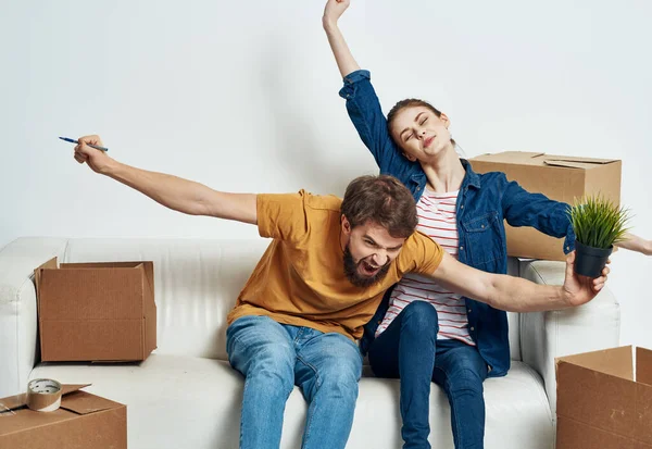 Cheerful young couple in the room on the couch with boxes moving