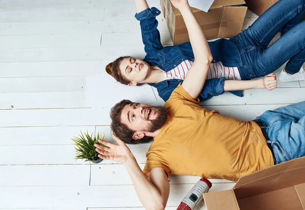 Hombre y mujer con cajas en el suelo una flor en una olla que se mueve para reparar el trabajo — Foto de Stock