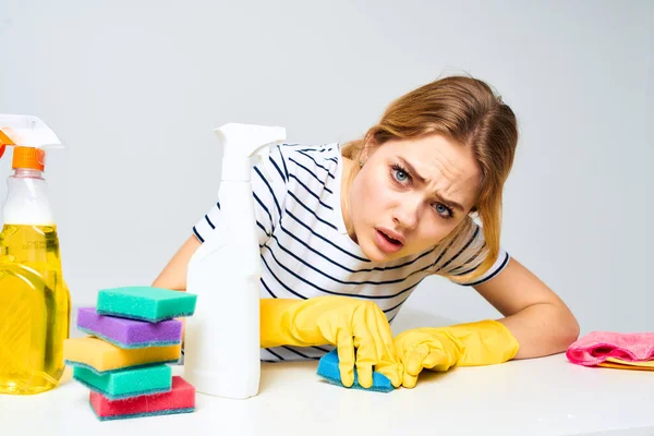 Alegre señora de limpieza limpia la mesa con detergentes herramientas de limpieza — Foto de Stock