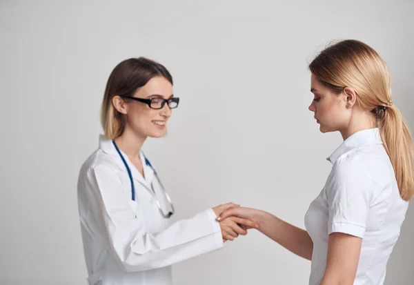 Профессиональная женщина-врач и пациент пожимают руку на светлом фоне — стоковое фото