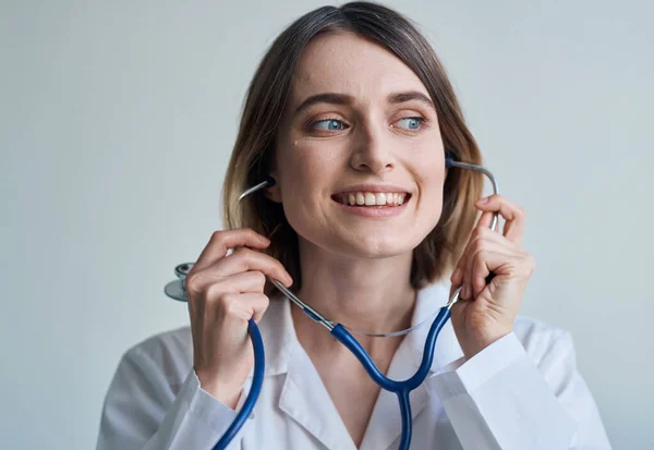 Professional doctor woman stands near the window and a stethoscope around her neck
