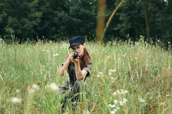 Γυναίκα με όπλο που στοχεύει προς τα εμπρός σε καταλήψεις σε πράσινα φύλλα εξωτερικού χώρου — Φωτογραφία Αρχείου