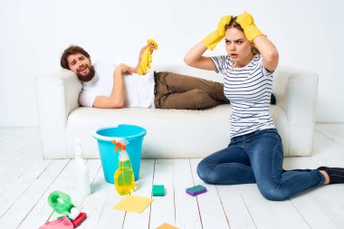 Kocası kanepede yatarken kadın temizlik yapar. Ev işleri.