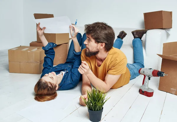 Hombre y mujer con cajas en el suelo una flor en una olla que se mueve para reparar el trabajo — Foto de Stock