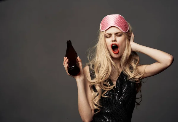 Mulheres com uma máscara de sono rosa seguram uma garrafa de cerveja na mão — Fotografia de Stock