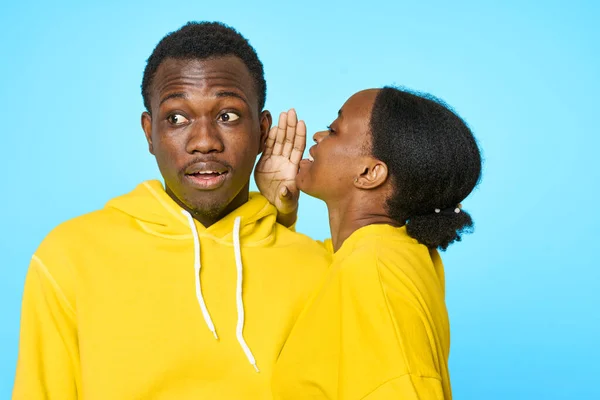 Uma mulher sussurra a um homem no ouvido de um jovem casal de aparência africana — Fotografia de Stock
