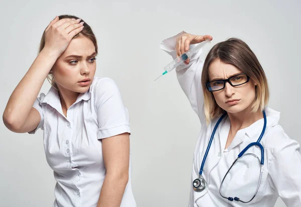 Переляканий пацієнт і медсестра з шприцом в руці на світлому фоні — стокове фото