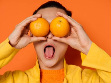 Gözlerinin önünde portakallar olan şaşırmış bir adam izole bir arka planda ağzını ardına kadar açtı.