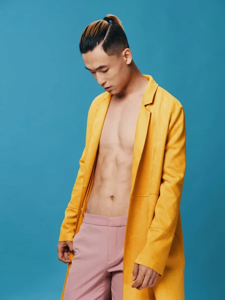 Chico guapo en una chaqueta amarilla en un torso desnudo y modelo de pantalones rosa —  Fotos de Stock