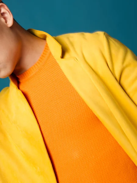 Egy férfi narancssárga pólóban és sárga dzsekiben, kék háttérrel, kivágott kilátással. — Stock Fotó