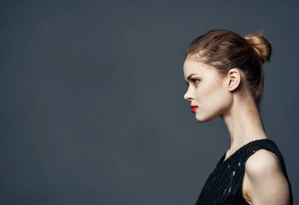 Side view of beautiful woman in black dress with hairstyle