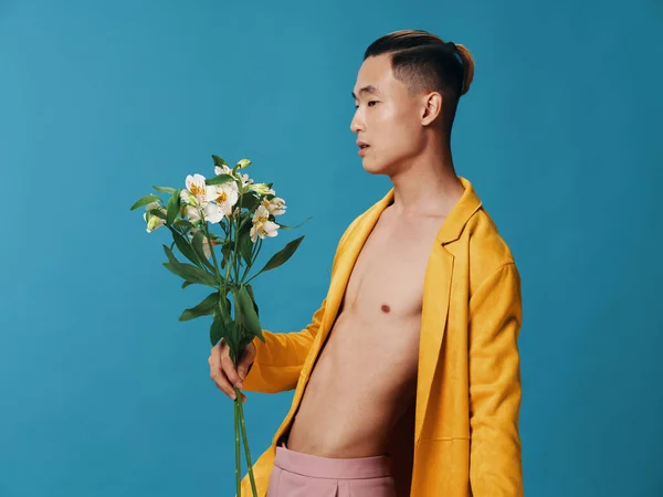 Retrato de um homem de casaco em um corpo nu e um buquê de flores azul fundo férias presentes — Fotografia de Stock