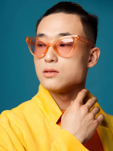 Retrato de un hombre con gafas Aspecto asiático chaqueta amarilla fondo azul —  Fotos de Stock