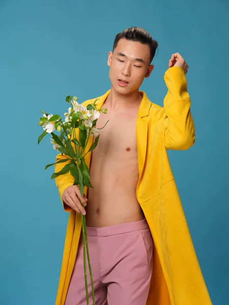 白い花の花束とピンクのズボンを持つハンサムな男は彼の手でジェスチャーしている — ストック写真