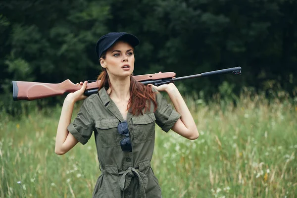 Mujer sosteniendo un arma detrás de su cabeza viajes de aire fresco caza de aire fresco árboles verdes — Foto de Stock