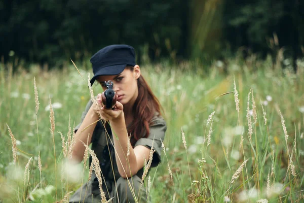 Mujer sentada al aire libre en la hierba apunta con un arma de refugio. armas — Foto de Stock