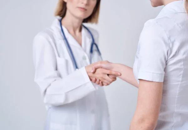 Dokter en patiënt schudden handen met elkaar op een lichte achtergrond bijgesneden uitzicht — Stockfoto