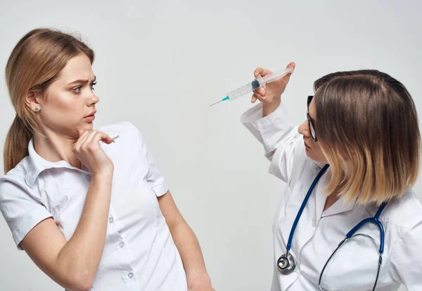 Женщина-врач показывает пациенту шприц и медицинское платье стетоскоп — стоковое фото