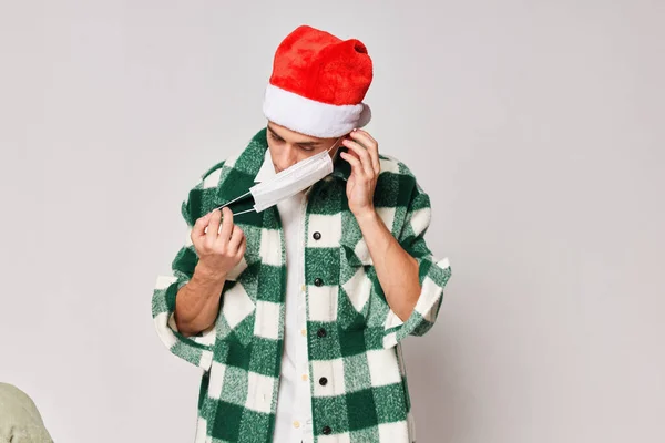 Man in green plaid shirt santa hat medical mask gray background — Stock Photo, Image