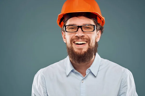 Bearded man in orange paint and glasses construction work blue background