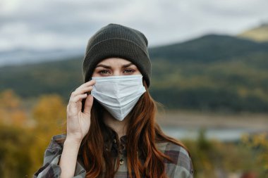 Sonbahar doğa arka planında tıbbi maskeli kadınlar dağ portresi.