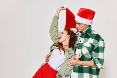 Bir erkek, bir kadını kollarında tutar. Noel şapkası, bayram duyguları. Dostluğun gri arka planını sunar.